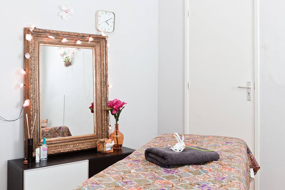 De behandelkamer: een spiegel met lichtjes, een dressoir en de behandeltafel met batikdoek en handdoek
